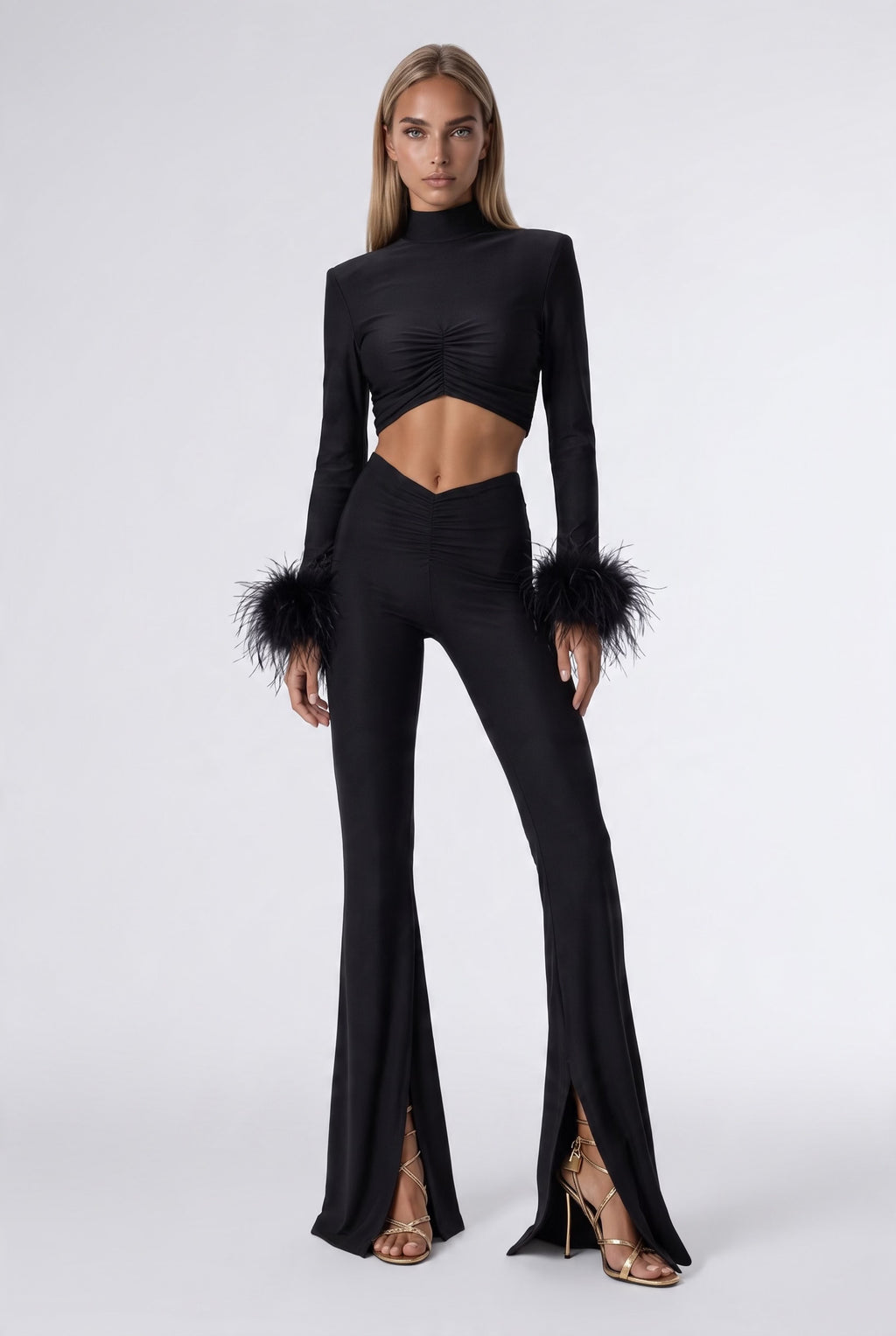 The Saint 54 black two-piece set with polo neck crop top, ostrich feather cuffs, and high-waisted flared trousers.