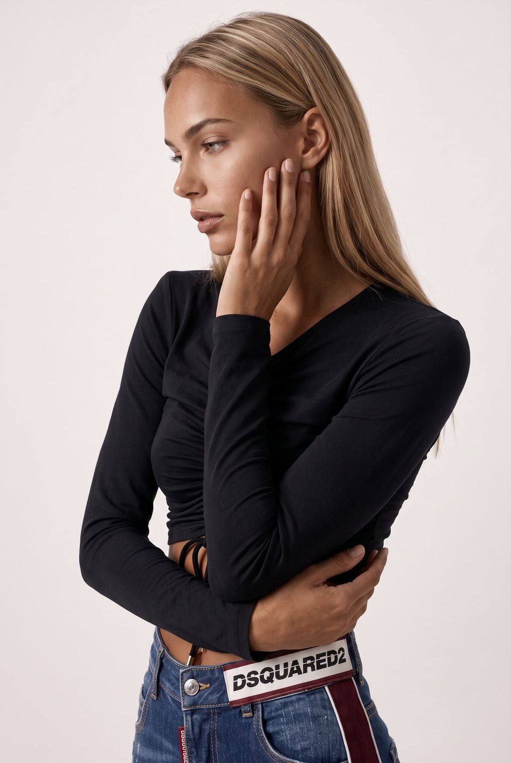The Saint 54 black long-sleeve crop top with shoulder pads, adjustable front ties, and gold-tone tips on a model.