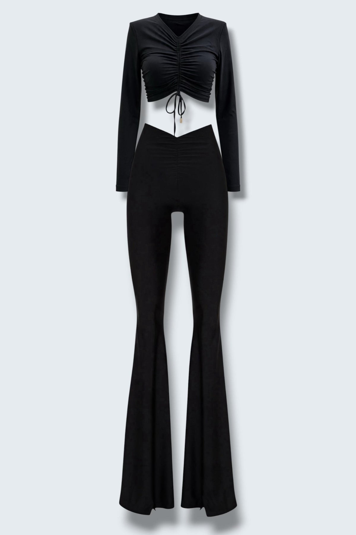 The Saint 54 black two-piece set featuring a long-sleeve ruched crop top and high-waisted flared trousers with slits.