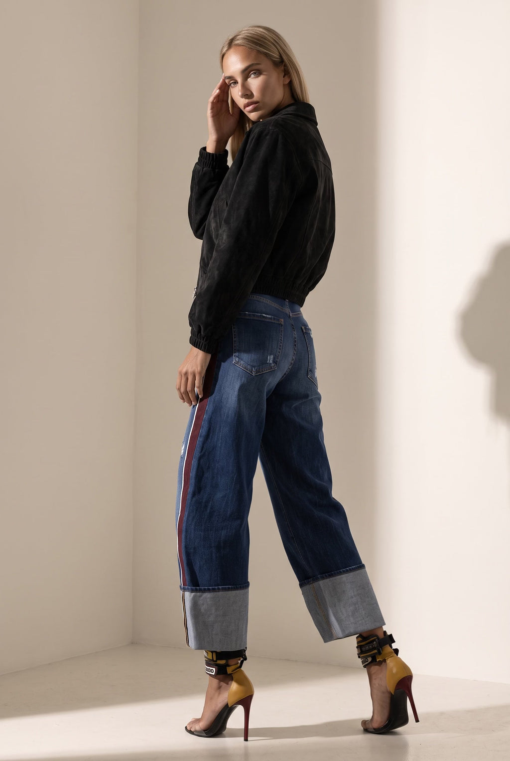 The Saint 54 black suede bomber jacket with an oversize fit, shoulder pads, and satin lining worn by a model.