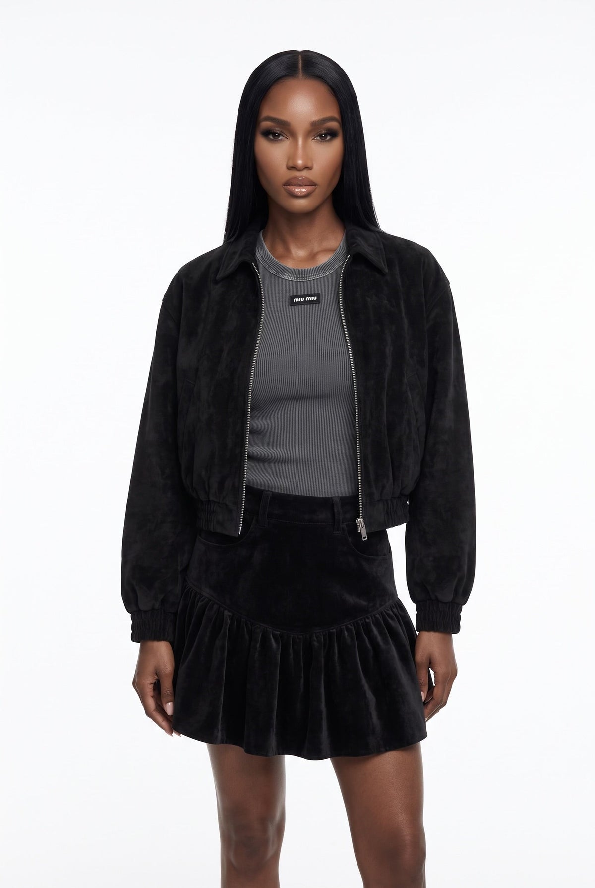 The Saint 54 black suede bomber jacket and ruffled mini skirt set worn by a model against a white background.