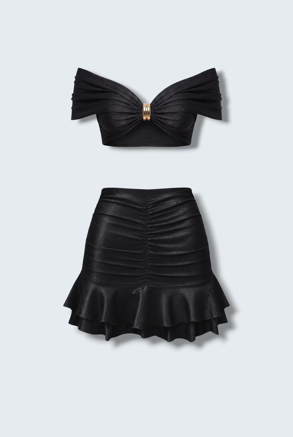 The Saint 54 black two-piece set featuring a cropped off-shoulder top with gold hardware and a ruffled mini skirt.