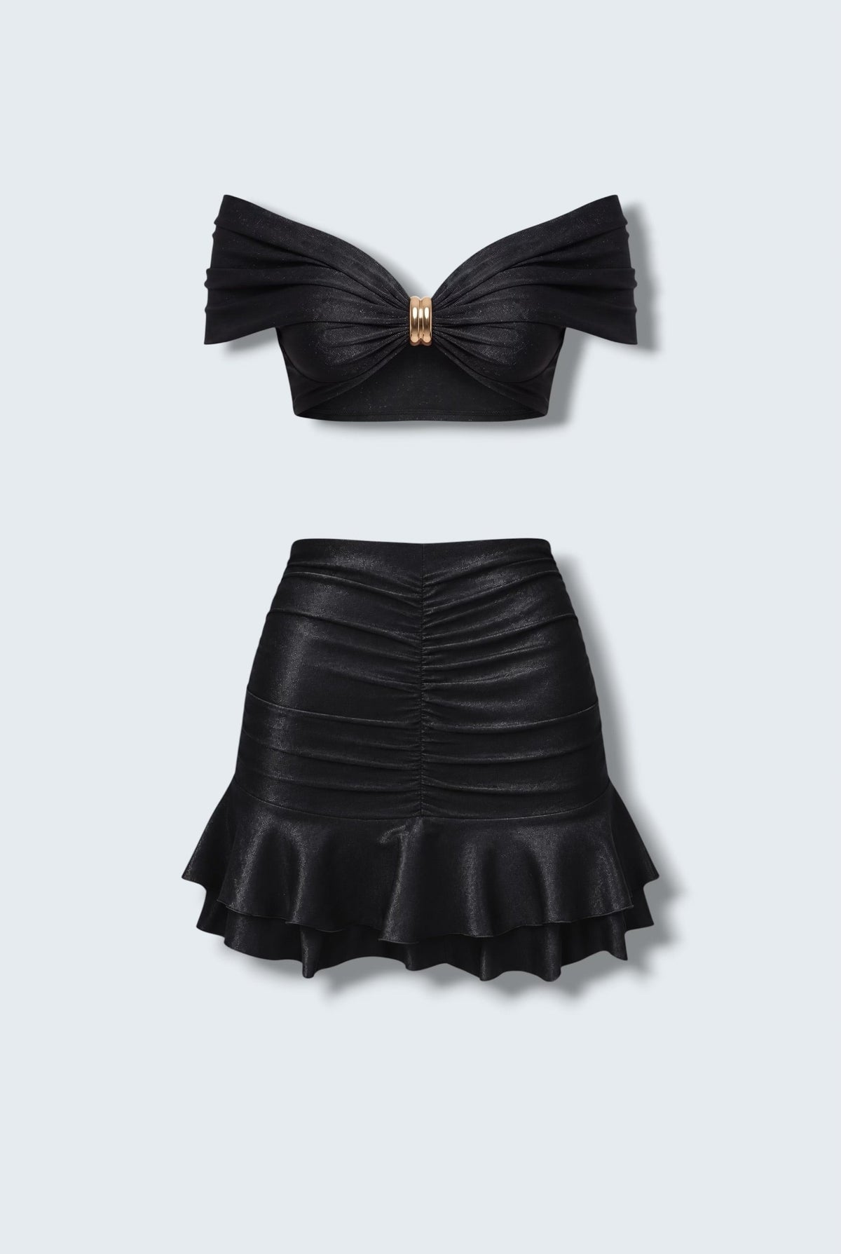 The Saint 54 black two-piece set featuring a cropped off-shoulder top with gold hardware and a ruffled mini skirt.