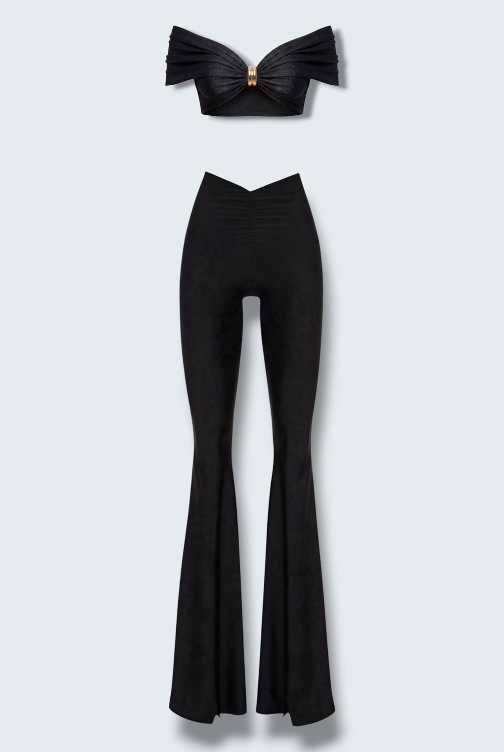 The Saint 54 black two-piece set featuring a cropped off-shoulder top with gold hardware and flared high-waisted pants.